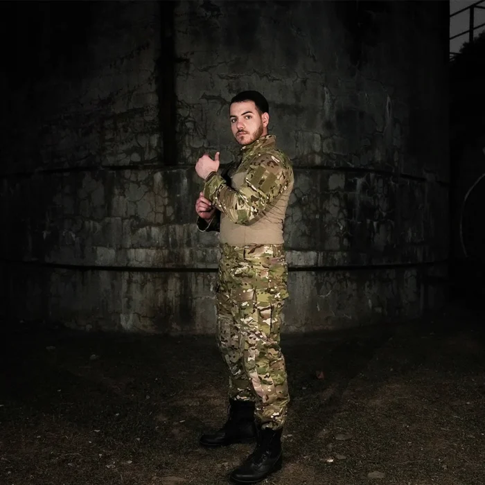 Model wearing camo uniform three-piece tactical suit, ideal for military training, outdoor survival, and airsoft combat scenarios.