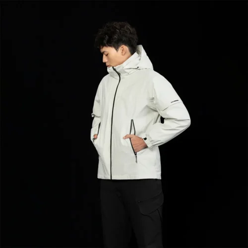 Model wearing men’s ivory white 3 in 1 waterproof jacket featuring a detachable fleece liner and windproof shell. Designed for outdoor activities and cool weather.