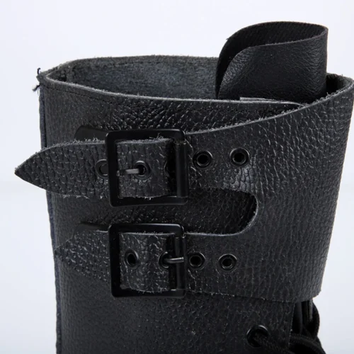 Detailed close-up of black leather combat boots featuring textured surface and durable buckle strap construction.