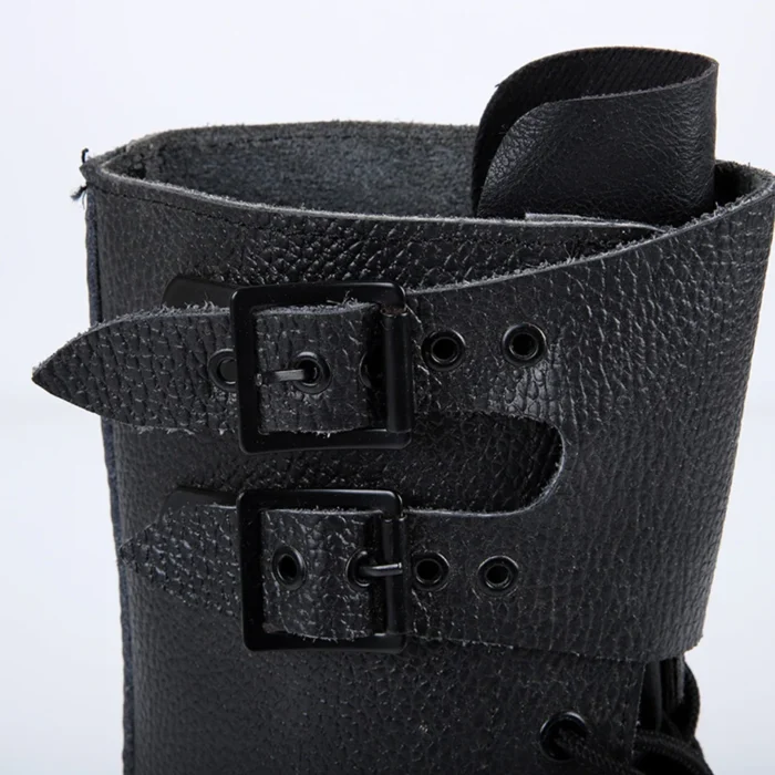 Detailed close-up of black leather combat boots featuring textured surface and durable buckle strap construction.