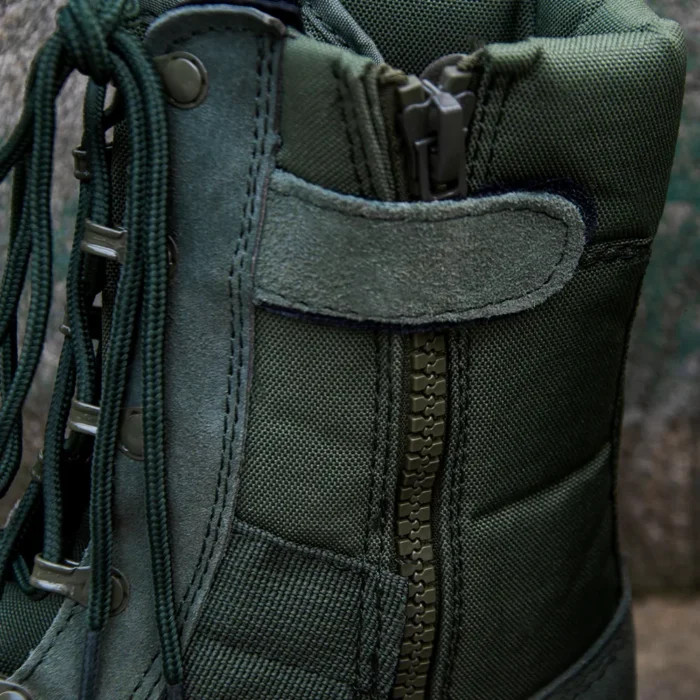 Close-up of green military boots showing reinforced stitching, side zipper design, and rugged fabric construction for outdoor performance.