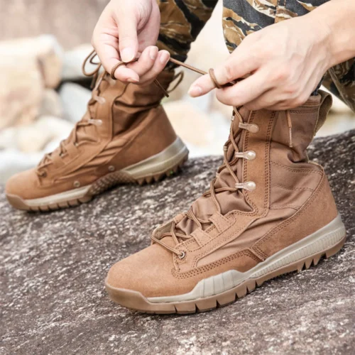 Person wearing tan combat boots on rocky terrain, featuring durable suede and breathable nylon for tactical or hiking use.