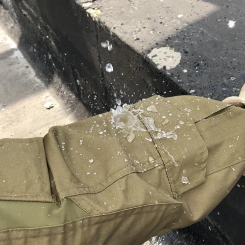 Waterproof test on tactical suit fabric showing strong water repellency and durable ripstop construction suitable for outdoor military use.