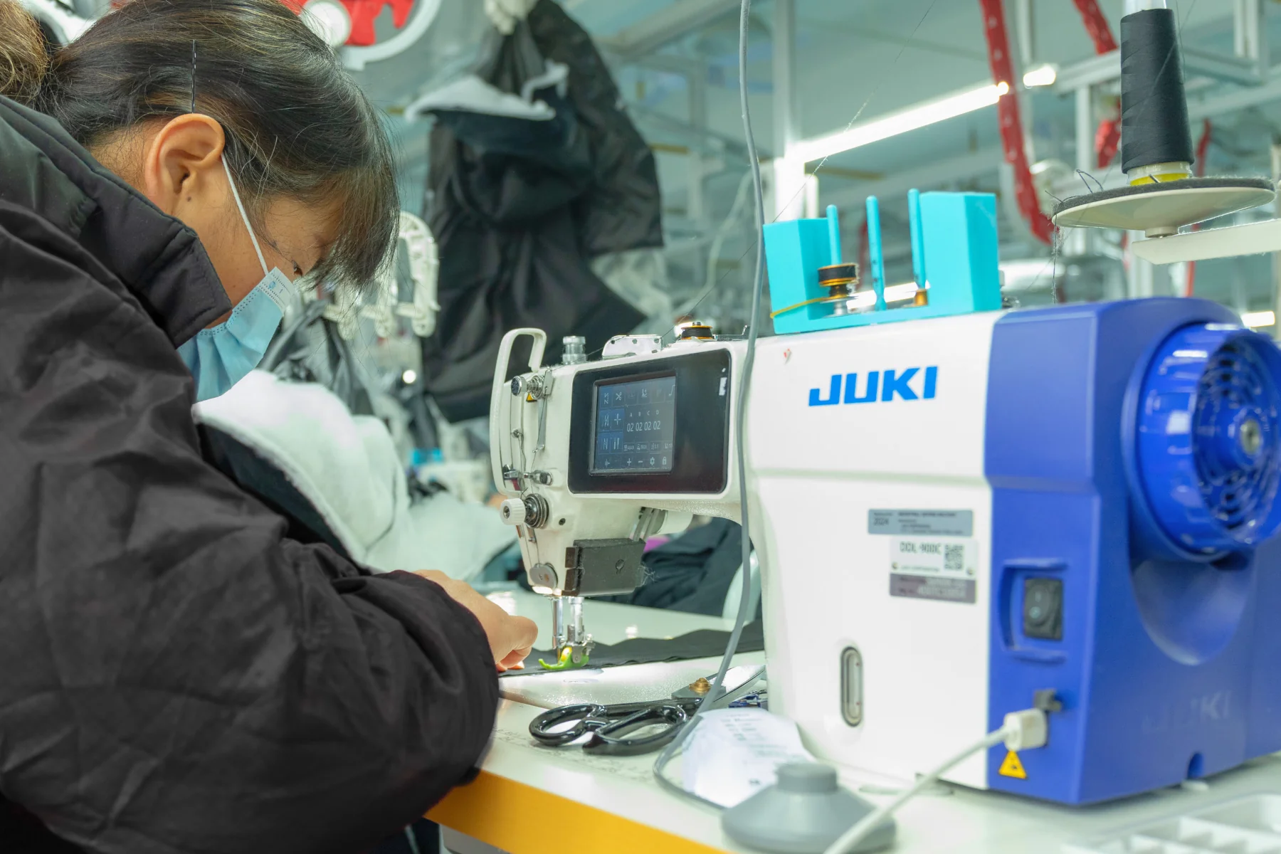 Worker sewing a garment sample on an industrial machine during the apparel prototyping process.