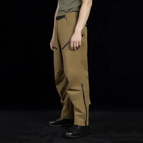 Side view of outdoor cargo pants highlighting zippered thigh pockets and flexible fabric construction for enhanced storage and movement in outdoor environments.