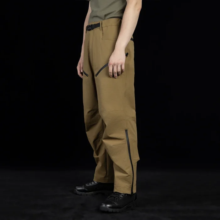 Side view of outdoor cargo pants highlighting zippered thigh pockets and flexible fabric construction for enhanced storage and movement in outdoor environments.