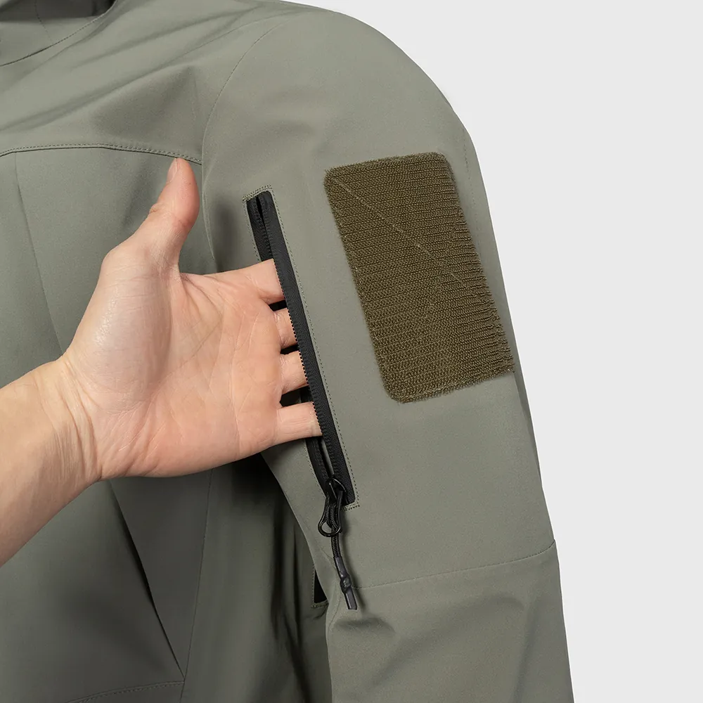 Detalhe do bolso com zíper na manga e do painel de identificação com fecho de velcro da jaqueta impermeável FM24230. Referência de construção e posicionamento da marca para produção OEM baseada em programa.